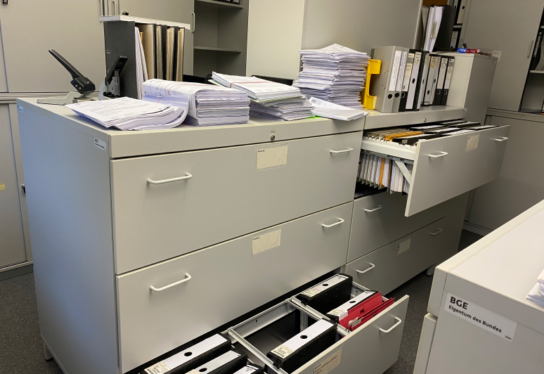 Vorher: Analoge Verfahren in der Produktkontrolle Aktenschrank mit Ordnern und Papier-Stapeln